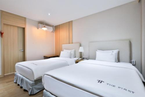 two white beds in a hotel room at The First Hotel in Changwon