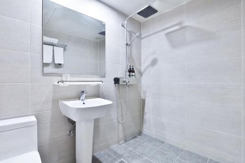 a white bathroom with a sink and a shower at The First Hotel in Changwon