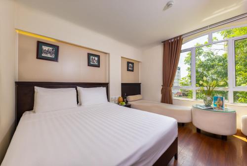 a bedroom with a bed and a desk and a window at Centre Point Hanoi Hotel in Hanoi