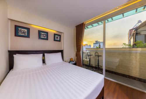 a bedroom with a bed and a large window at Centre Point Hanoi Hotel in Hanoi