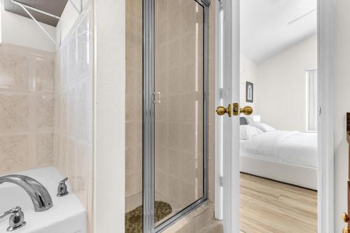 a bathroom with a shower and a sink and a bed at Disney Area 4BR Home with Heated Private Pool in Kissimmee