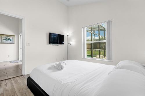 a white bedroom with a large bed and a window at Disney Area 4BR Home with Heated Private Pool in Kissimmee