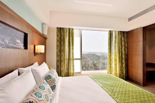 a hotel room with a bed and a large window at Fairfield by Marriott Belagavi in Belgaum