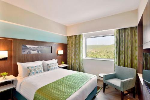 um quarto de hotel com uma cama e uma cadeira e uma janela em Fairfield by Marriott Belagavi em Belgaum