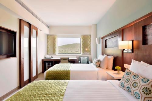 a hotel room with two beds and a window at Fairfield by Marriott Belagavi in Belgaum