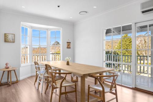 a dining room with a table and chairs and windows at Hygge House in Kangaroo Valley