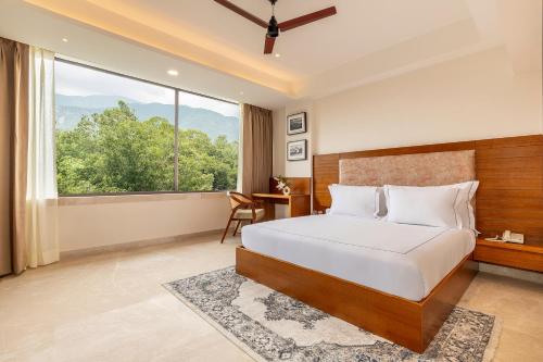 a bedroom with a large bed and a large window at The Prominence Mussoorie Road Dehradun in Dehradun