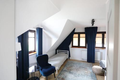 ein Schlafzimmer mit einem Bett und einem blauen Stuhl in der Unterkunft Nowodworski in Nowy Dwór Gdański