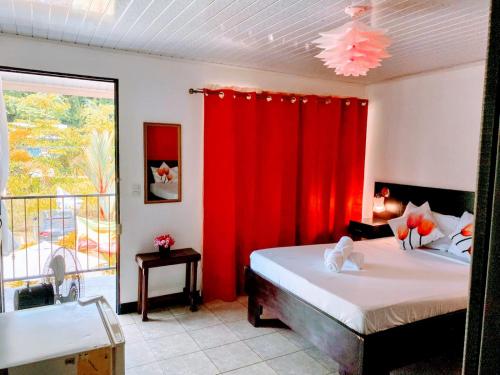 a bedroom with a bed with red curtains and a window at Roca Mar ROCAWELCH Puerto Viejo in Puerto Viejo
