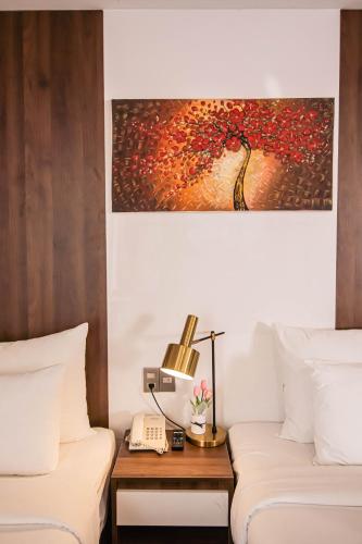 a hotel room with two beds and a table with a lamp at Gold Central Hotel by Haviland in Da Nang