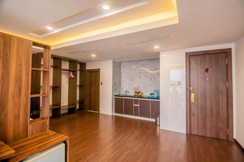 a living room with a wooden door and a kitchen at Gold Hotel Da Nang by Haviland in Da Nang