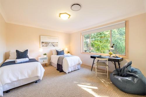1 Schlafzimmer mit 2 Betten, einem Schreibtisch und einem Fenster in der Unterkunft White Sands, 14 Whitesands Road - Pet Friendly & Air Con in Fingal Bay