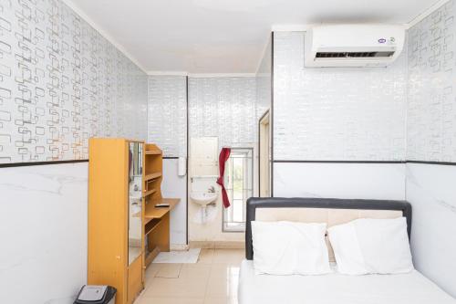 a small bedroom with a bed and a sink at Alfa Guesthouse Serpong Mitra RedDoorz in Tangerang