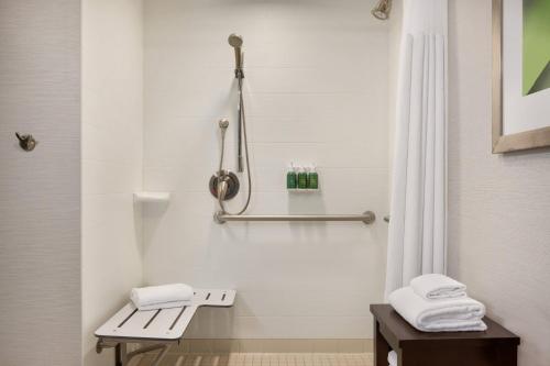 a bathroom with a shower with a bench and towels at Courtyard Greenville in Greenville