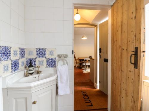 a bathroom with a white sink and a hallway at Lucky Cottage in Foxt