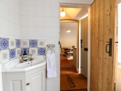un bagno con lavandino bianco e corridoio di Lucky Cottage a Foxt