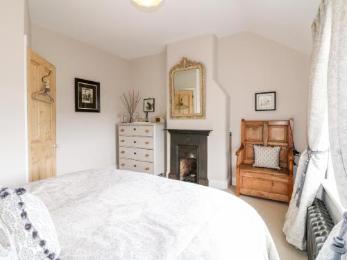 a white bedroom with a bed and a fireplace at Lucky Cottage in Foxt