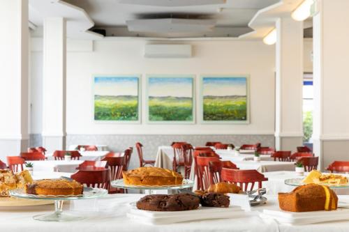 une salle remplie de tables et de chaises avec des gâteaux sur les assiettes dans l'établissement Hotel Plaza, à Cattolica