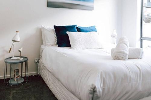 a white bed with blue pillows in a bedroom at Anchored@Bicheno - Ohmyview! in Bicheno