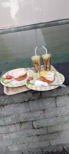 two plates with sandwiches and two cups on a table at D'La CoCo Villa in Bangli
