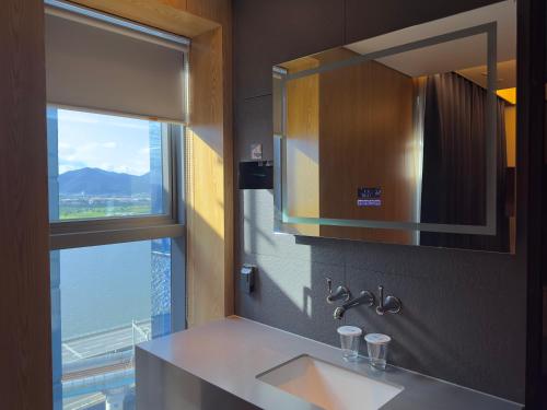 a bathroom with a sink and a mirror and a window at Hotel tt Gupo in Busan