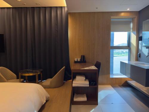 a bedroom with a bed and a desk and a window at Hotel tt Gupo in Busan