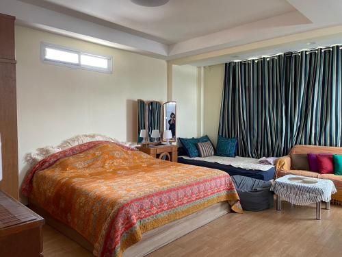 een slaapkamer met een bed en een bank bij Gumpuju คำปู้จู้ in Chiang Mai