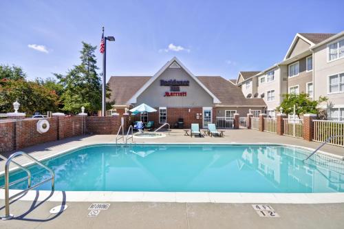 a swimming pool in a courtyard with a building at Residence Inn by Marriott Jacksonville Airport in Jacksonville
