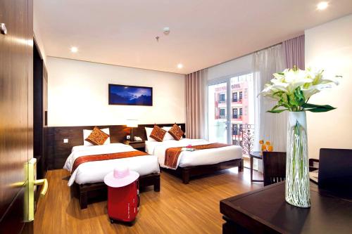 um quarto de hotel com duas camas e um vaso de flores em Edele Hotel em Nha Trang