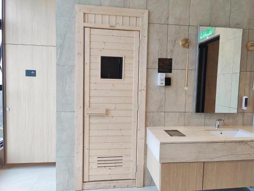 a bathroom with a wooden door next to a sink at Axon Residences Bukit Bintang in Kuala Lumpur