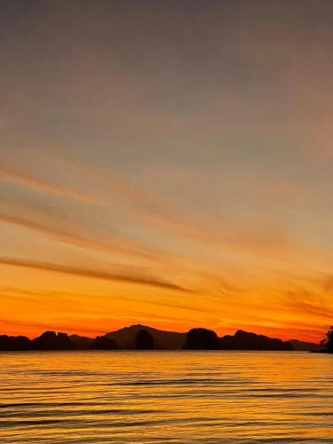 a sunset over the water with mountains in the background at Hillhouse - Koh Yao Noi in Ko Yao Noi