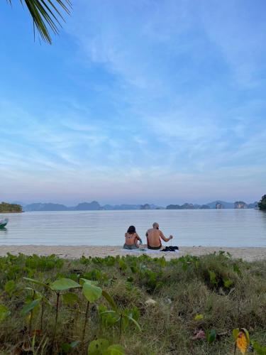 two people sitting on the beach near the water at Hillhouse - Koh Yao Noi in Ko Yao Noi