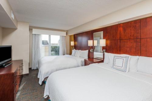 a hotel room with two beds and a flat screen tv at Residence Inn Orlando Airport in Orlando