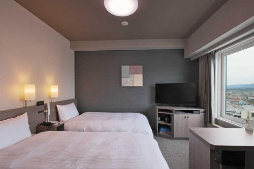 中野市にあるホテルルートインGrand中野小布施のベッド2台、薄型テレビが備わるホテルルームです。