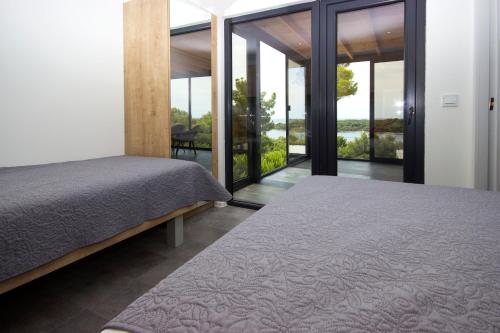 sypialnia z 2 łóżkami i przesuwnymi szklanymi drzwiami w obiekcie KastHouse Luxury mobile home Anika w miejscowości Mali Lošinj
