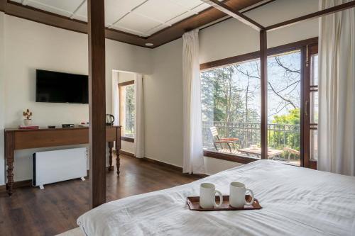 una camera da letto con un letto e una grande finestra di StayVista at Pine Estate with Outdoor Jacuzzi a Shimla