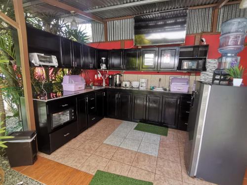 a kitchen with black cabinets and a refrigerator at Roca Mar ROCAWELCH Puerto Viejo in Puerto Viejo