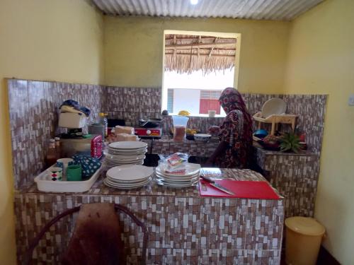 a woman standing in a kitchen with a table full of plates at Magharibi House in Nungwi