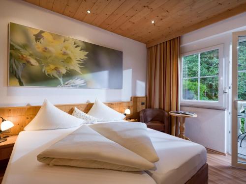 a bedroom with a white bed with a painting on the wall at Aparthotel Gallahaus in Zell am Ziller