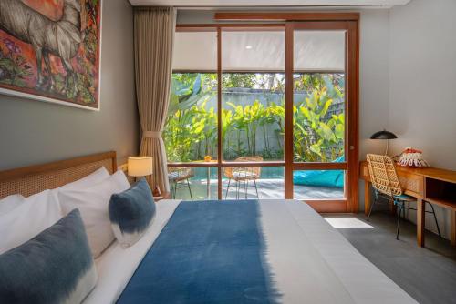 a bedroom with a bed and a desk and a window at Ecozy Dijiwa Canggu in Canggu