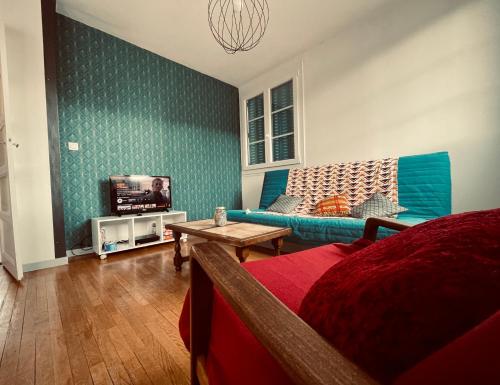 ein Wohnzimmer mit einem blauen Sofa und einem TV in der Unterkunft Le Nid des Ducs - Gare et Cité gastronomique in Dijon