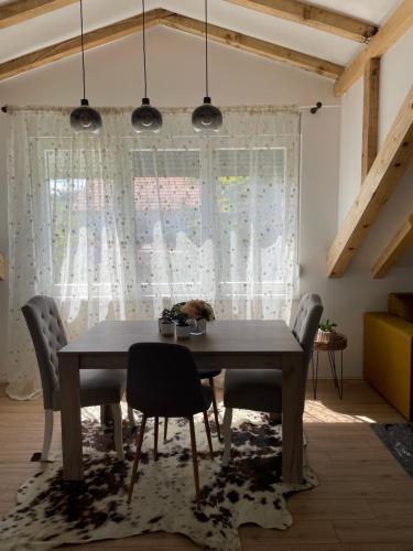 ein Esszimmer mit einem Tisch, Stühlen und einem Fenster in der Unterkunft Naš san in Vrdnik