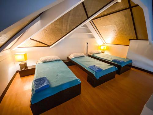 two beds in a room with an attic at Kavanah Suites Guinhawa Tagaytay in Tagaytay