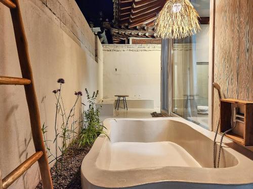 a bath tub in a room with a chandelier at Relax House in Gyeongju