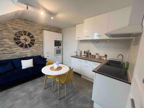 uma cozinha e sala de estar com uma mesa e um sofá azul em Appartement « My love » em Sainte-Savine