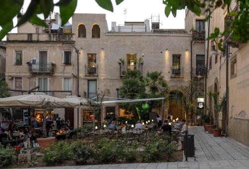 a building with people sitting at tables in a courtyard at Sofi' Center Rooms in Sciacca