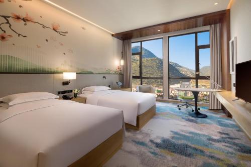 ein Hotelzimmer mit 2 Betten und einem TV in der Unterkunft Hilton Garden Inn Nujiang in Lushui