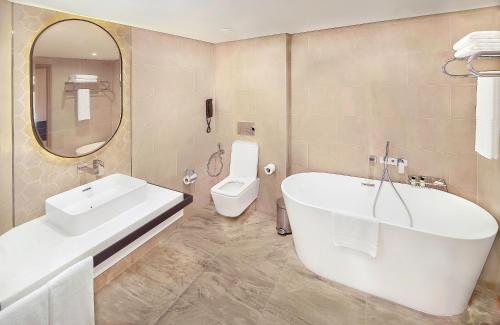 a bathroom with a tub and a sink and a toilet at Sheraton Abu Dhabi Hotel & Resort in Abu Dhabi