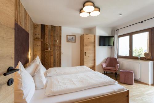 um quarto com uma cama, uma cadeira e uma televisão em Appartements SonnAlm em Berwang