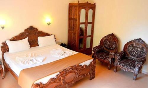 a bedroom with a large bed and two chairs at FabExpress VT Resort With Pool, Calangute Beach in Calangute